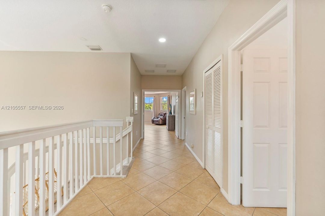 Hallway featuring tile flooring, white baluster railing, and recessed lighting