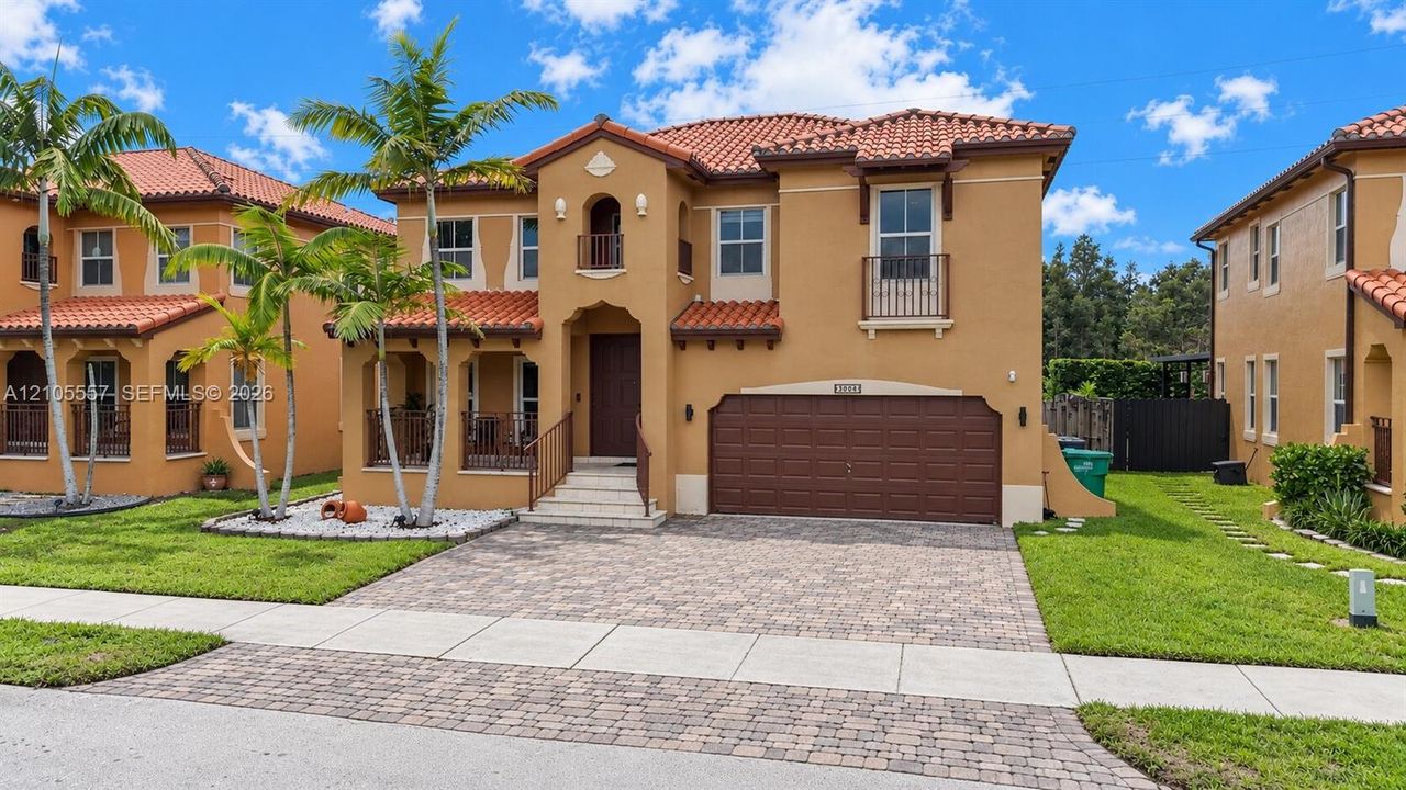 Mediterranean-inspired exterior with a terracotta tile roof, stucco finish, and an arched entry