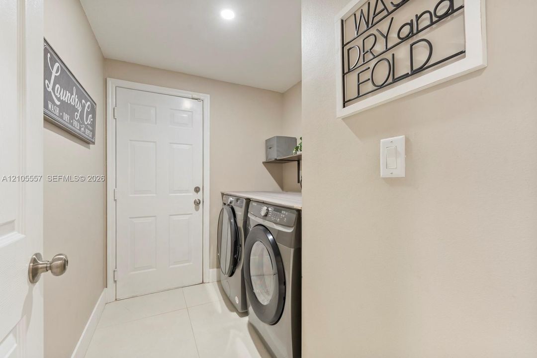 Laundry area featuring white paneled doors, tile flooring, a built-in shelf, and recessed lighting