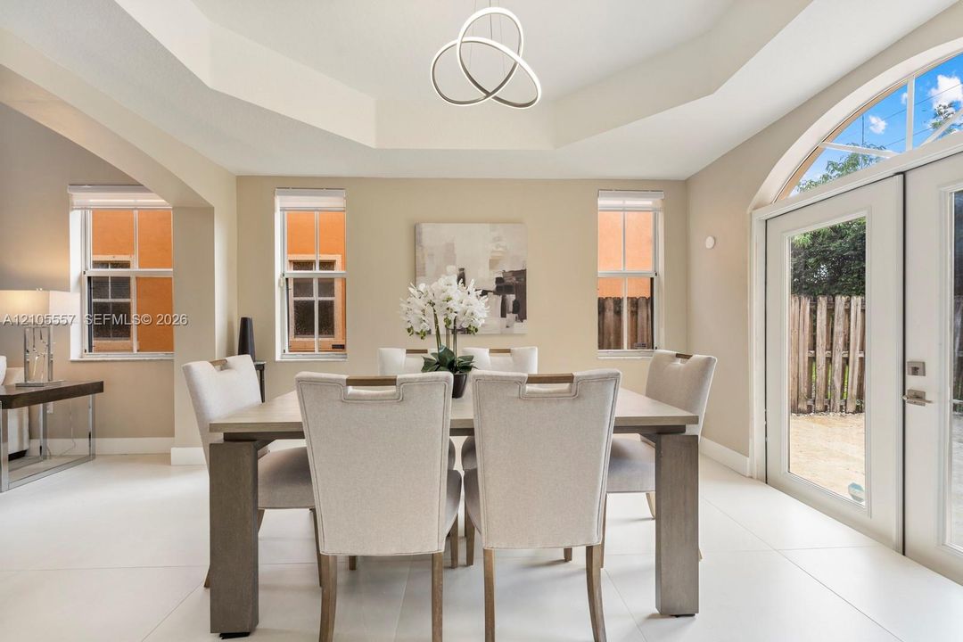 Tray ceiling with a modern pendant light fixture, light-toned walls, and white tile flooring