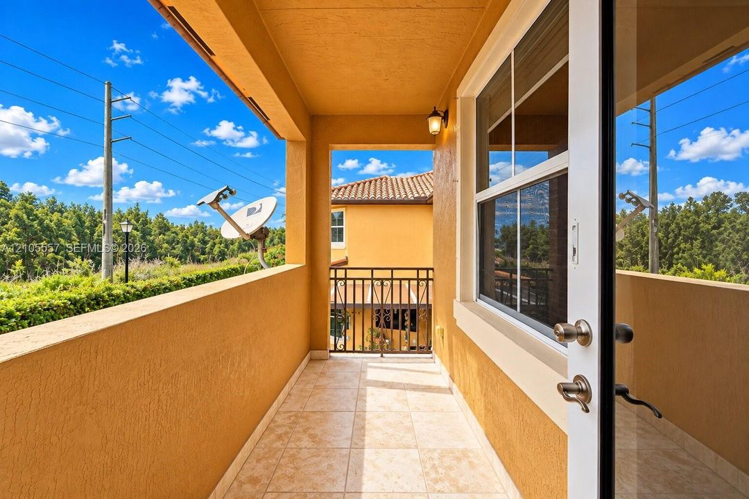 Outdoor balcony with tile flooring, stucco exterior, and a wrought iron railing