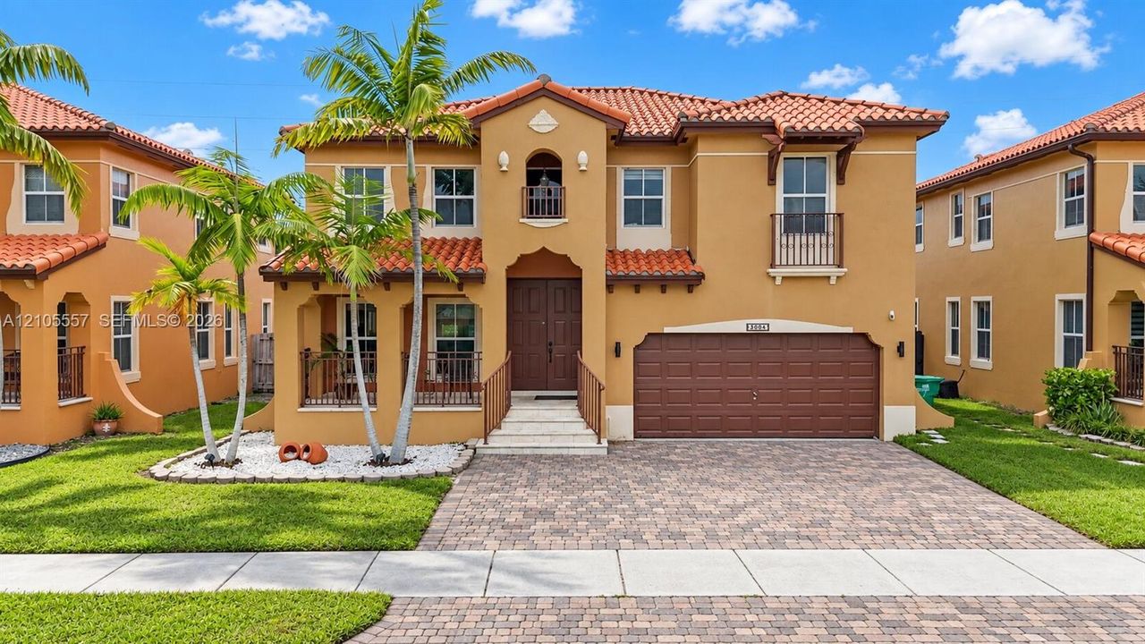 Mediterranean-style exterior with a terra cotta tile roof, stucco finish, and an integrated two-car garage