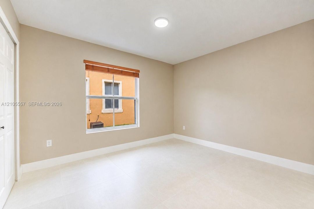 Recessed lighting, neutral wall tones, large window, wood-finish window treatments, and light-toned tile flooring