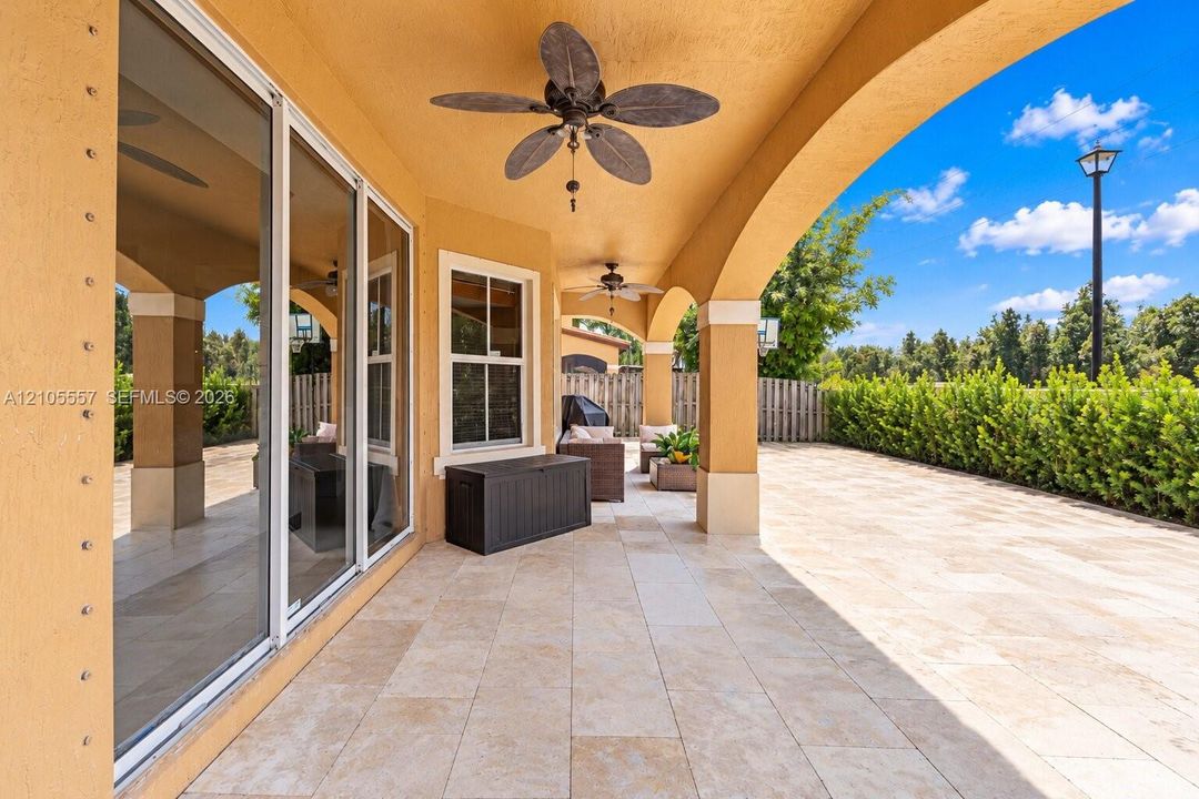 Expansive covered patio with arched supports, ceiling fans, and large format tile flooring