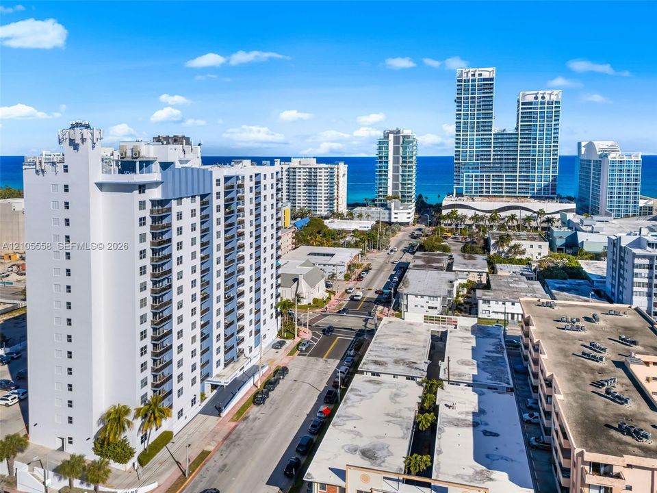 High-rise building with multiple balconies, a structured rooftop, and established palm trees at the base