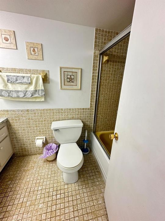 Bathroom featuring a built-in bathtub with a sliding glass enclosure, mosaic tile flooring, and mosaic wall tiling