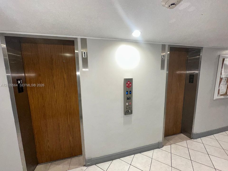 Two elevator doors featuring wood-finish panels and stainless steel frames