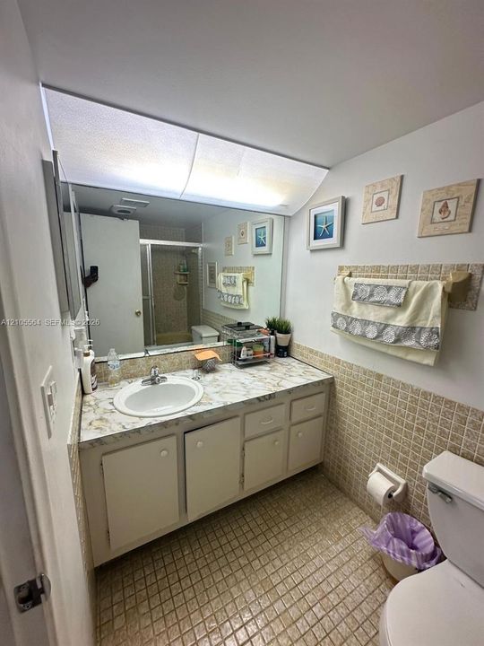 Single vanity with a white basin sink, integrated mirror, and built-in cabinetry