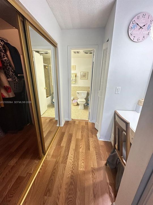 Wood-finish flooring, mirrored sliding closet doors, and a built-in desk area