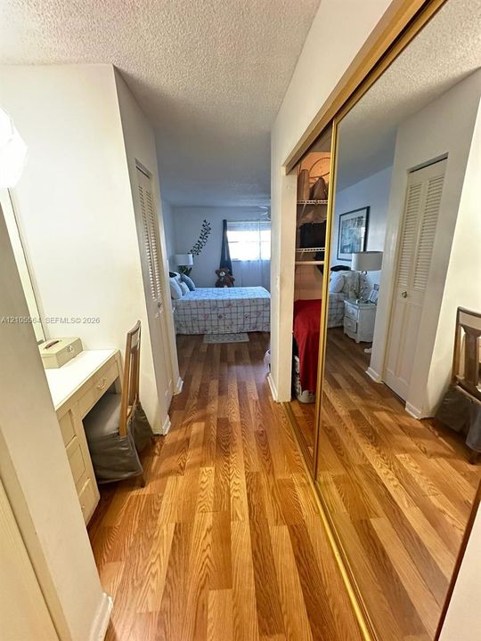 Wood-finish flooring throughout, full-height mirrored sliding closet door, and white louvered closet doors