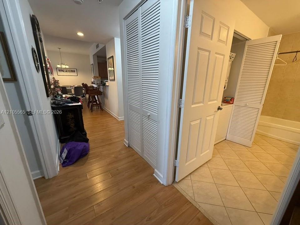 Wood-finish flooring, white louvered closet doors, and ceramic tile flooring