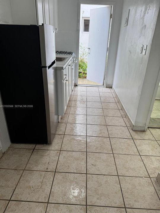 Tile flooring, white cabinetry, integrated sink, stainless steel refrigerator, and built-in stovetop