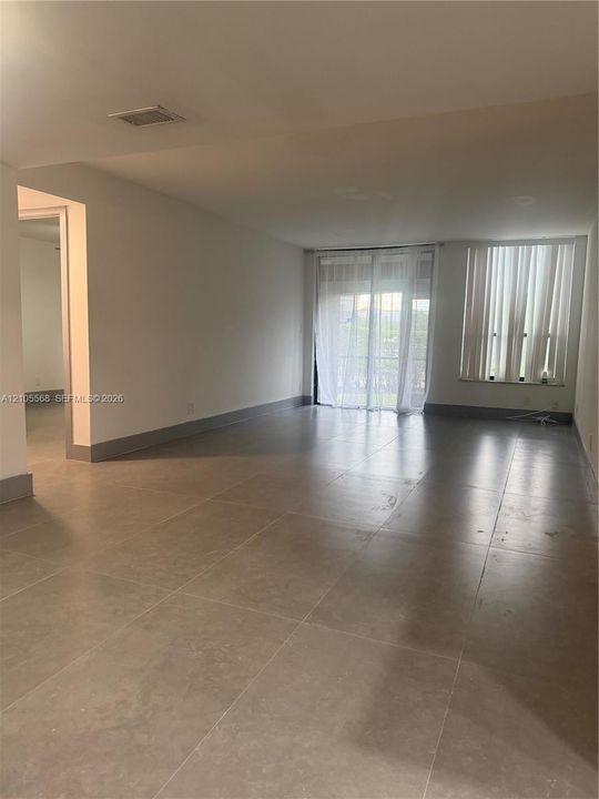 Spacious room featuring neutral tile flooring, white walls, and abundant natural light from multiple windows