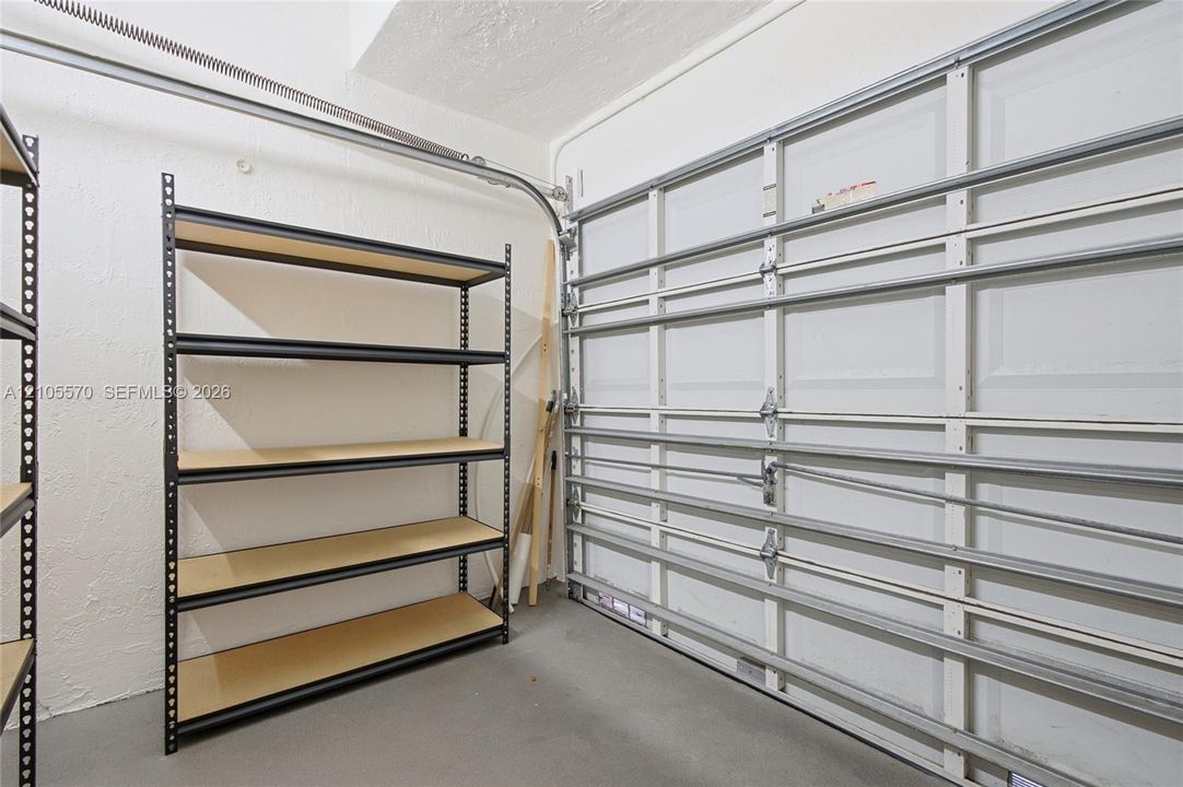 Garage space featuring a roll-up door, exposed track system, and concrete flooring