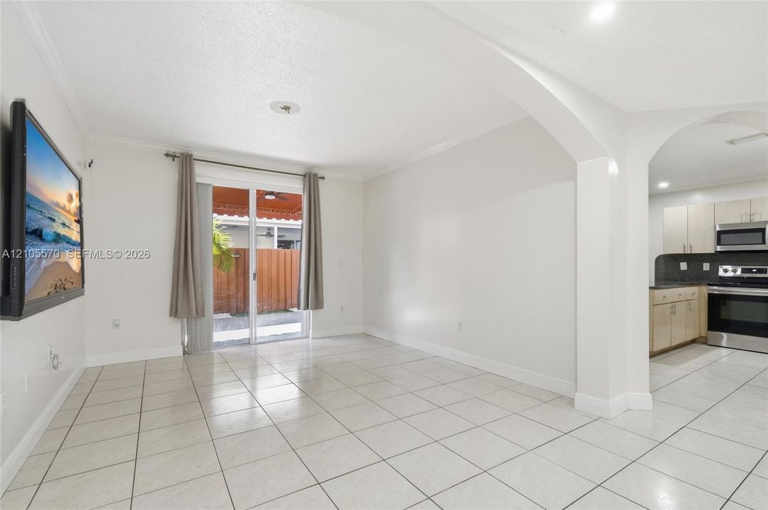 Tile flooring, sliding glass door, recessed lighting, arched entryway, and kitchen with stainless steel appliances
