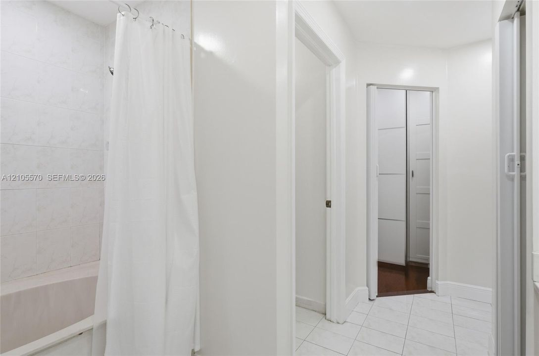 White rectangular floor tiling, white wall paint, and white paneled doors