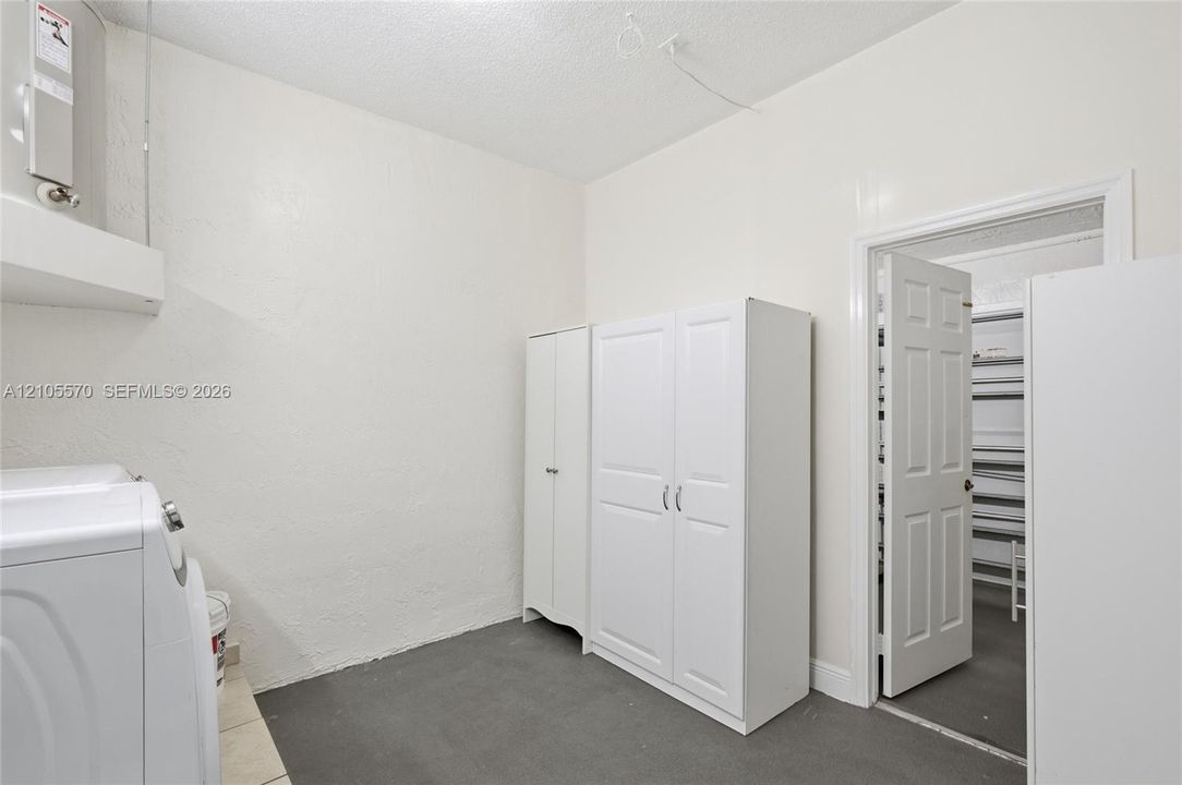 Functional utility space with a white paneled door, built-in shelving, and white cabinetry