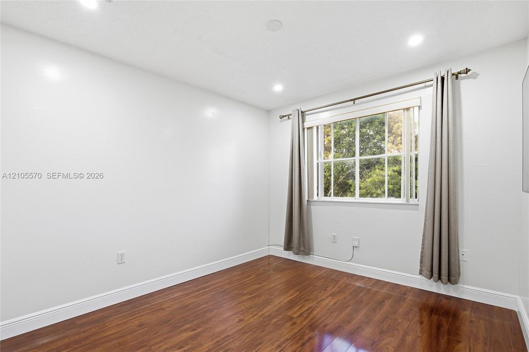 Recessed lighting, wood-finish flooring, white baseboards, and a double-hung window