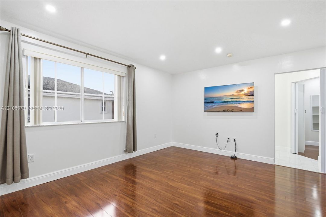 Recessed ceiling lighting, wood-finish flooring, and a window with white trim