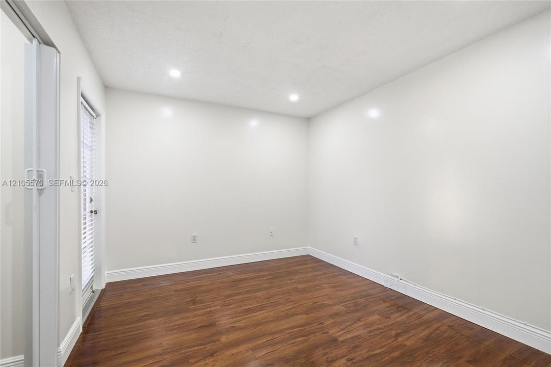 Wood-finish flooring, recessed lighting, and a white interior door with integrated blinds