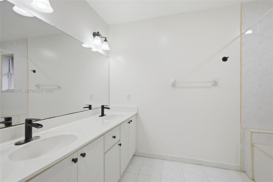 Dual vanity with matte black faucets, white countertops, and integrated sinks