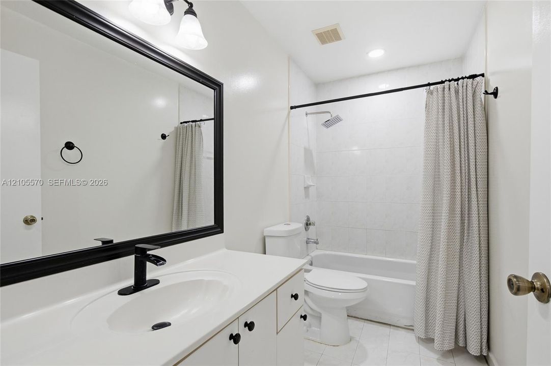 Bathroom featuring a vanity with an integrated sink, matte black faucet, and a large framed mirror