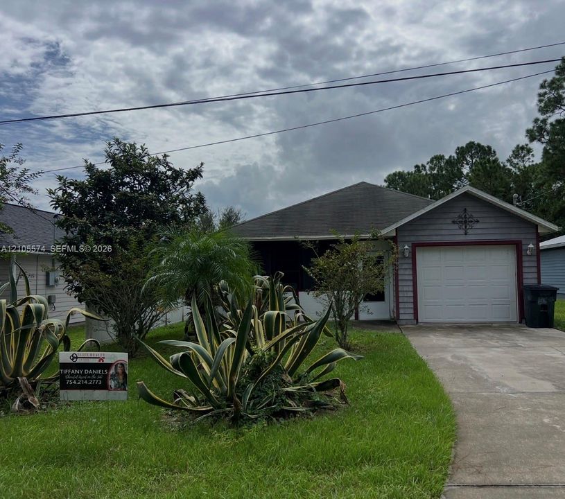 Single-story residence featuring horizontal lap siding, a front-facing attached garage, concrete driveway, and mature landscaping