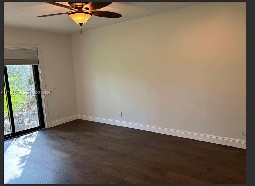 Wood-finish flooring, sliding glass door with integrated blinds, and ceiling fan with integrated light fixture