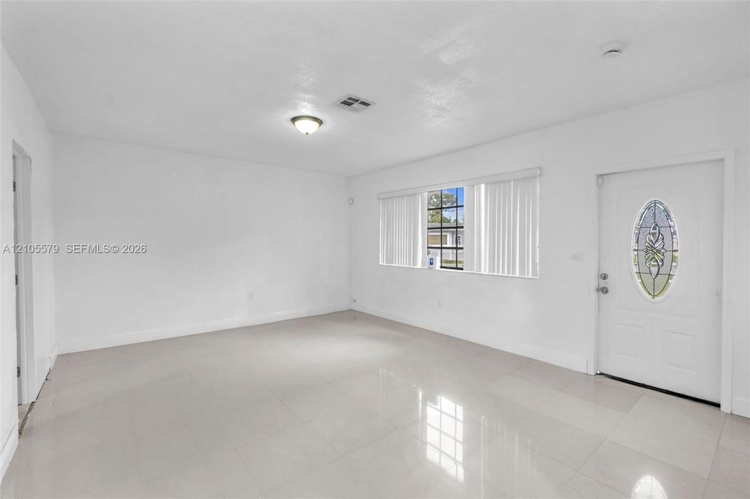 Neutral-toned tile flooring, large multi-pane windows, and an entry door featuring an oval decorative glass insert