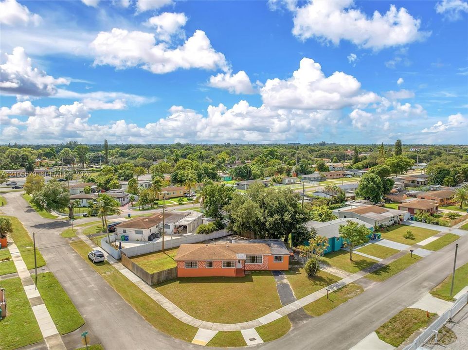 Corner lot residence featuring a paved driveway, exterior stucco finish, and a shingle roof