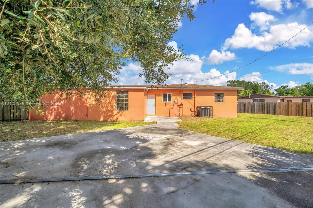Exterior of the residence featuring a concrete driveway, masonry walls, horizontal fencing, and a concrete patio