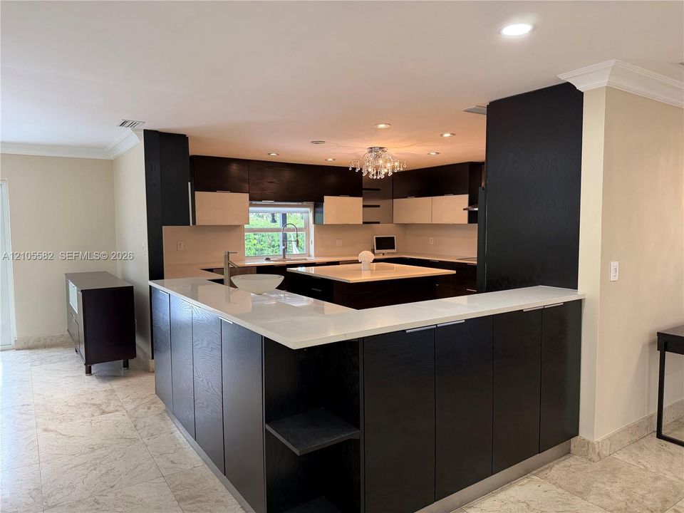 Kitchen featuring dark wood-finish cabinetry, light countertops, and a central island with a vessel sink
