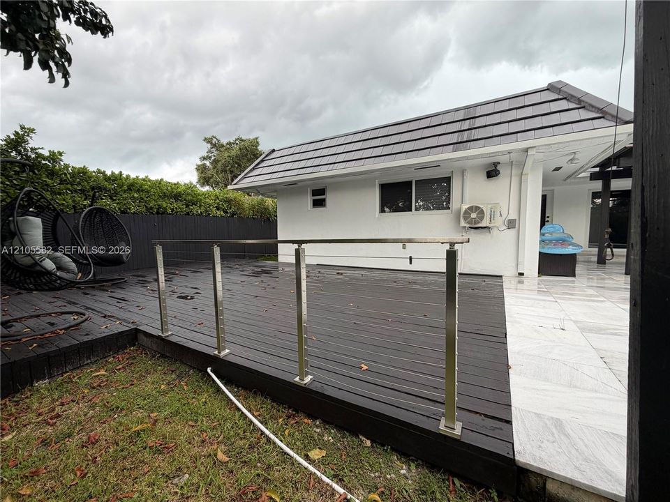Expansive outdoor deck featuring dark wood-finish planking and stainless steel railings