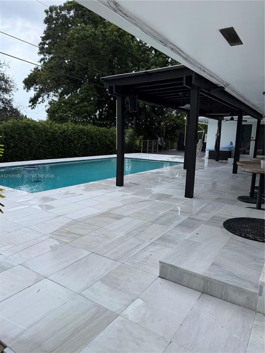 Large format light-toned patio pavers with a swimming pool
