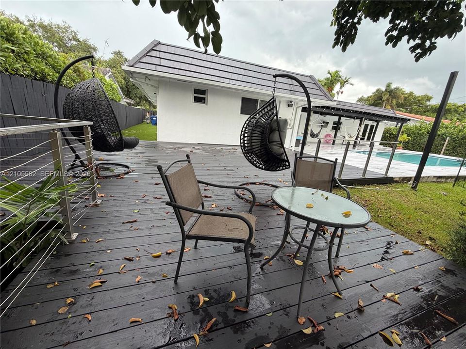 Expansive wooden deck with cable railings and a tiled roof structure