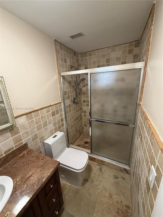 Tiled shower enclosure with a glass sliding door, complete with a shower head and handheld sprayer