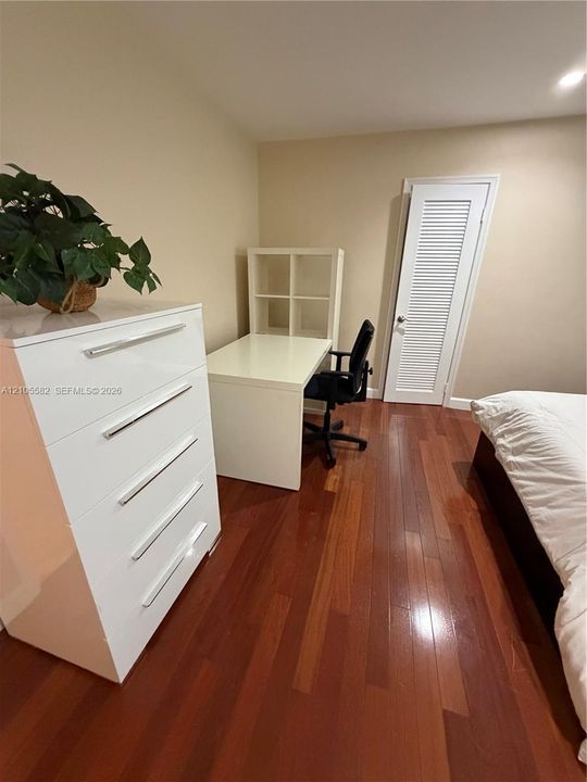 Rich wood flooring, neutral wall tones, and a built-in louvered door