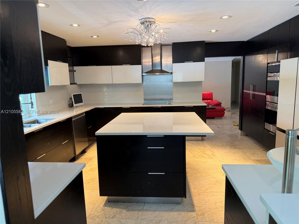 Modern kitchen featuring dark wood-finish cabinetry, white countertops, and a crystal chandelier