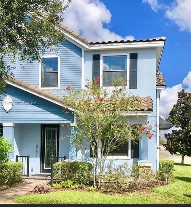 Two-story exterior featuring a mix of horizontal lap siding and smooth stucco finish, clay tile roof sections, decorative window shutters, and a glass-paneled entry door
