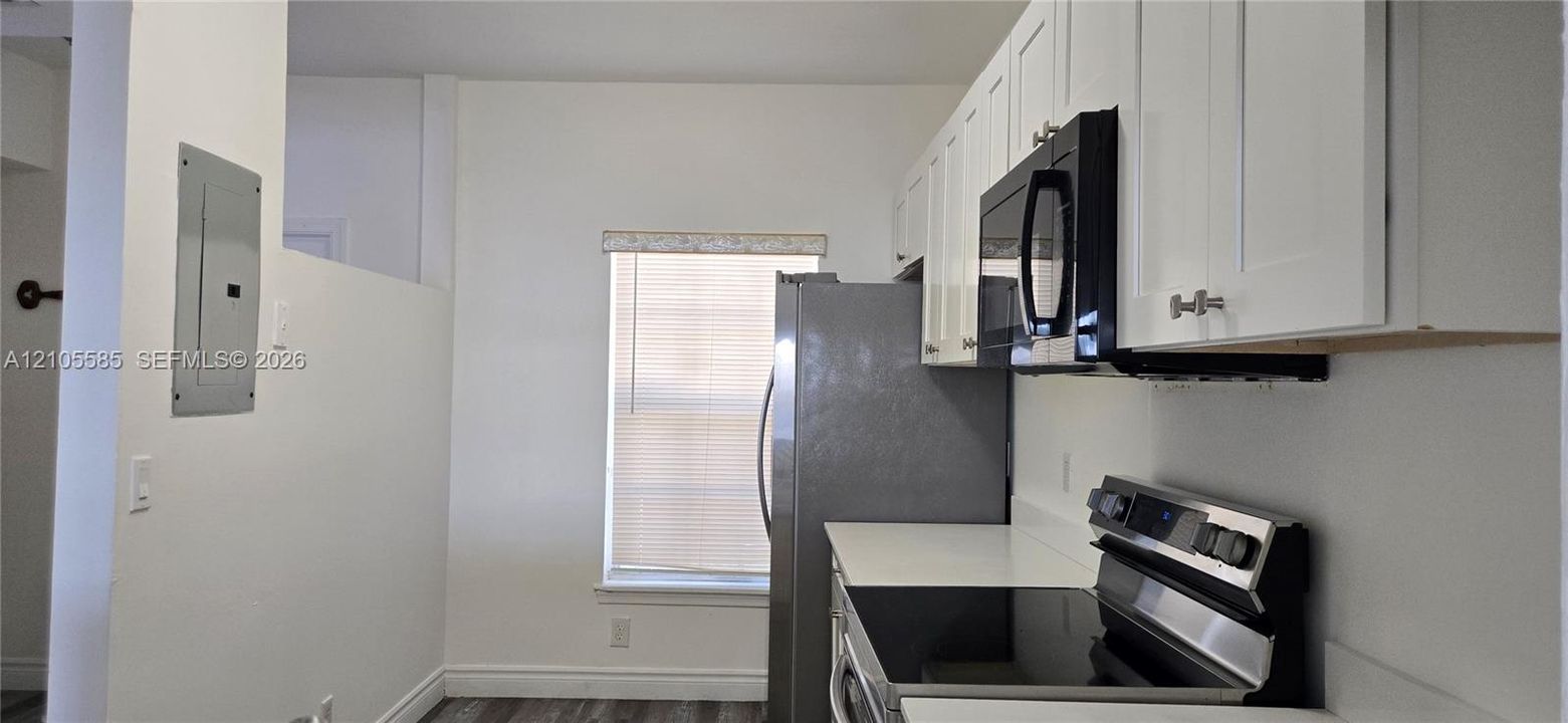 Kitchen featuring white Shaker-style cabinetry, stainless steel appliances, a glass-top range, and a neutral countertop