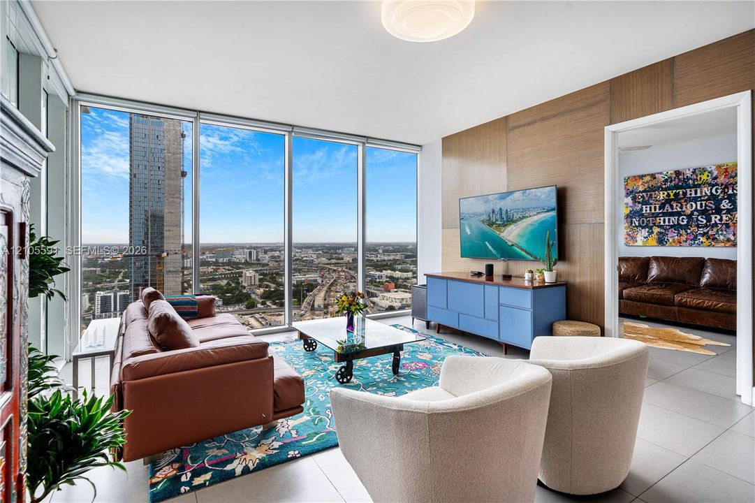 Floor-to-ceiling windows, wood-finish accent wall, ceiling-mounted lighting fixture, and light tile flooring
