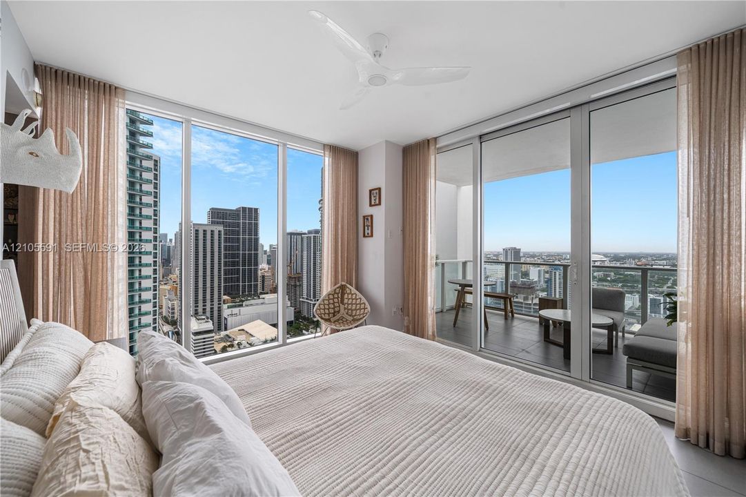 Floor-to-ceiling windows, sliding glass door to a private balcony, ceiling fan, and recessed lighting