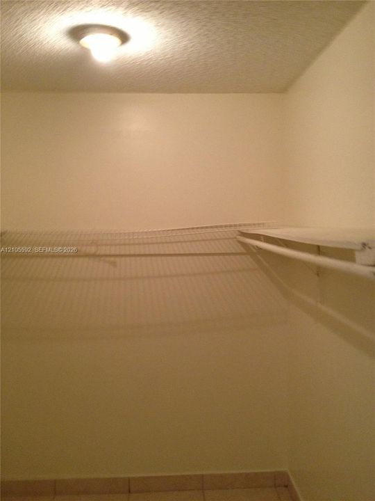 Recessed lighting, textured ceiling, light-toned wall paint, wire shelving, tile flooring