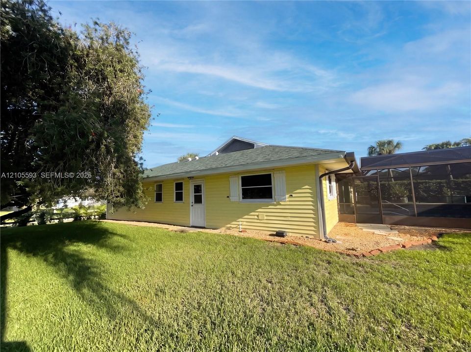 Exterior featuring yellow siding, shutter-accented windows, a shingled roof, and an enclosed screened-in area