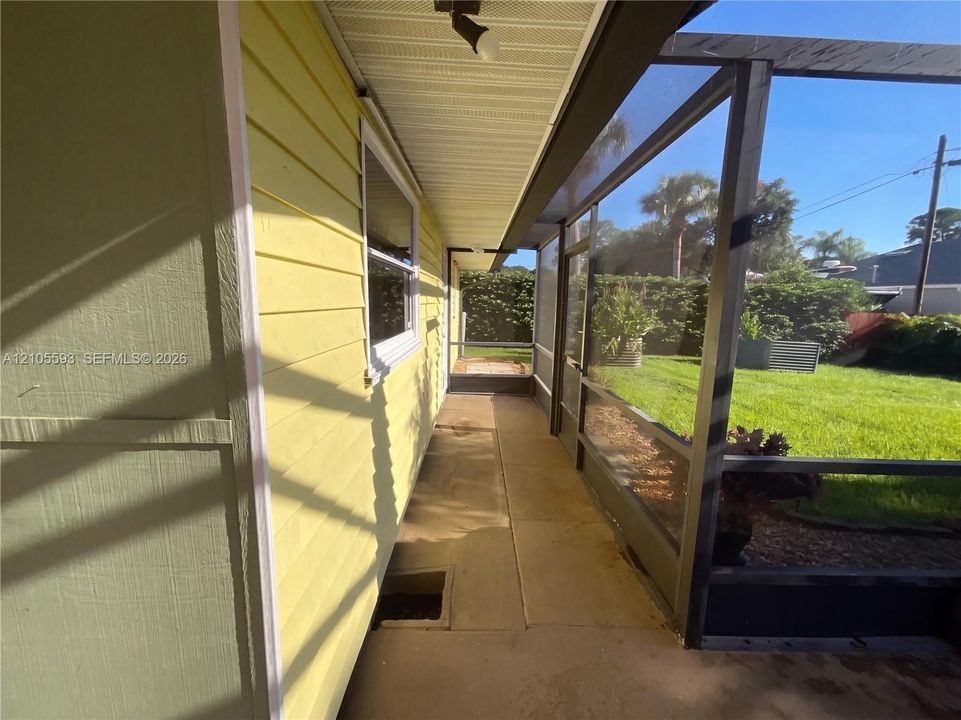 Screened-in porch featuring horizontal lap siding, a concrete floor, and direct access to an open grass yard