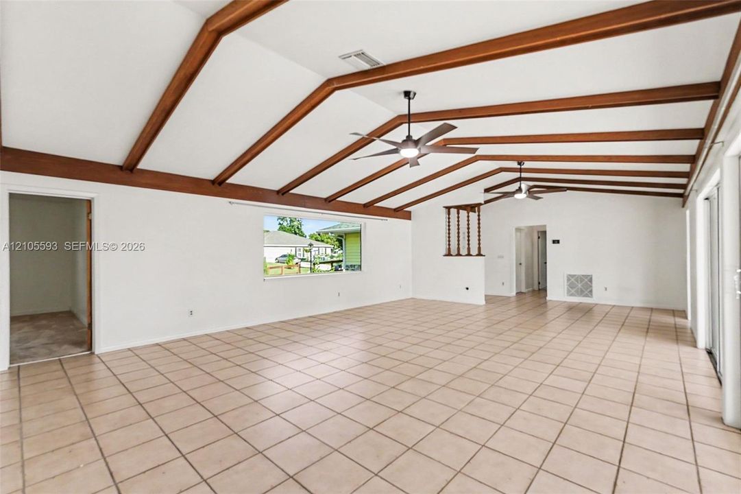 Vaulted ceiling featuring exposed wood beams, ceramic tile flooring, and dual ceiling fans