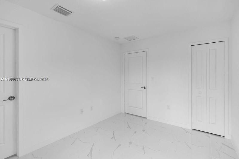 Interior room featuring large-format veined flooring, two-panel interior doors, and a double-door closet