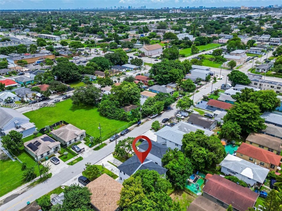 Aerial perspective of a multi-story residence with a pitched shingle roof, integrated solar panels, and perimeter landscaping