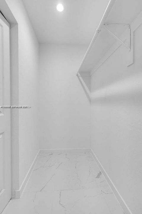 Storage space featuring large-format tile flooring with a veined pattern, built-in shelving, and recessed ceiling lighting