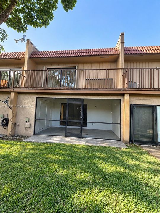 Screened patio, upper-level balcony with railings, sliding glass doors, tile roof, and stucco exterior